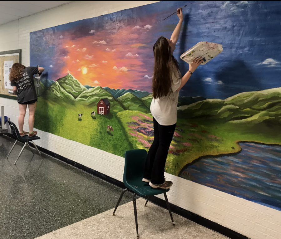 Senior Chloe Wakefield painting her capstone project on one of the hallway walls at Loudoun Valley