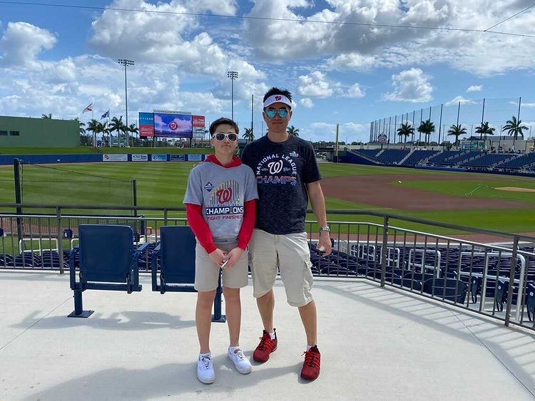 Sage Lin  stands with his father (on the right, Lin on the left) at a Nationals Spring training game last spring prior to Covid-19 lockdown.
