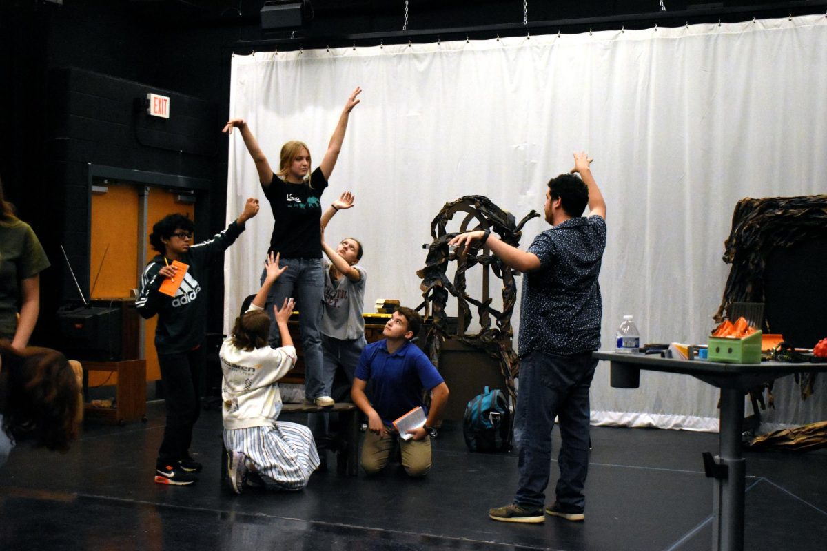 Senior Sydney Sheehan and the cast of "The Legend of Sleepy Hollow" rehearse making a tree shape to be silhouetted during the final performance